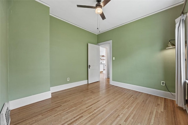empty room with wood finished floors, crown molding, baseboards, baseboard heating, and ceiling fan