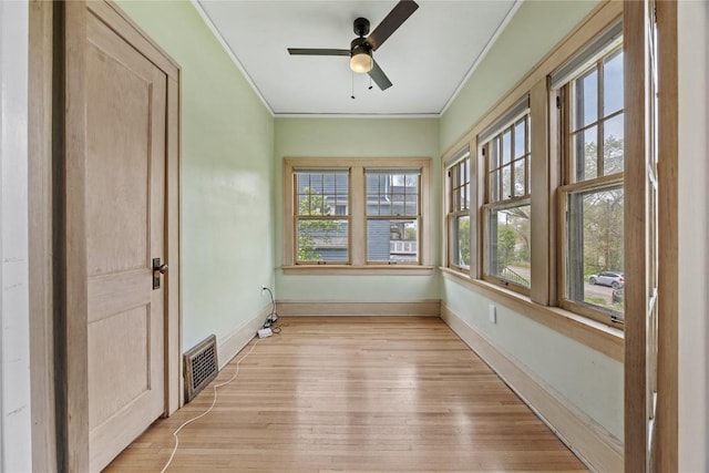 unfurnished sunroom with crown molding, visible vents, wood finished floors, and baseboards