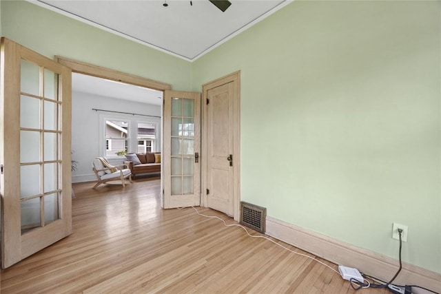 empty room with light wood-type flooring, visible vents, french doors, and baseboards