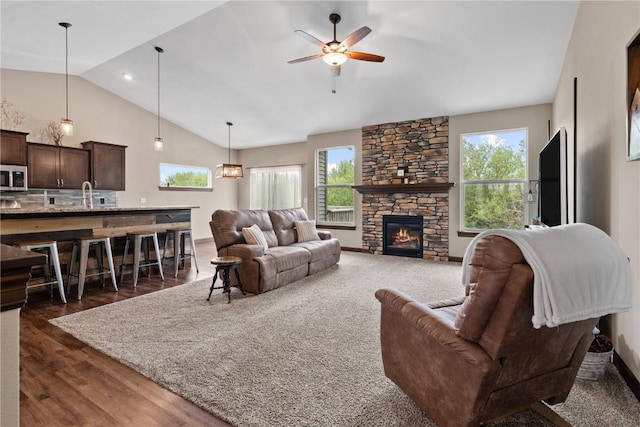 living area featuring a fireplace, dark wood-style flooring, lofted ceiling, and a ceiling fan