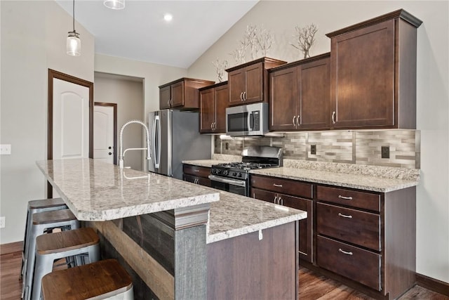 kitchen featuring a center island with sink, decorative backsplash, appliances with stainless steel finishes, and dark wood-style floors
