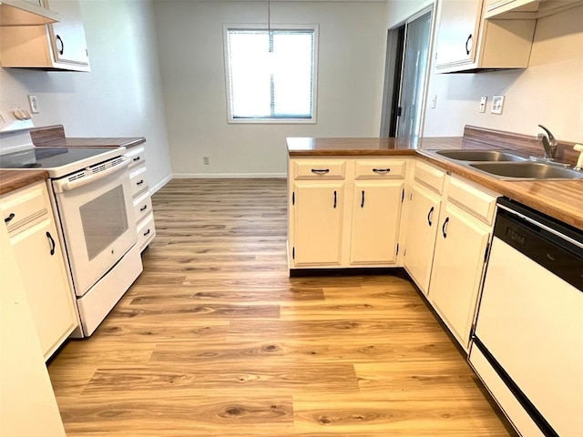 kitchen with a sink, a peninsula, white appliances, light wood-style flooring, and baseboards