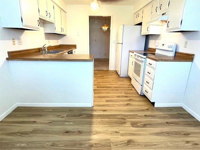 kitchen featuring a sink, white appliances, under cabinet range hood, light wood finished floors, and dark countertops