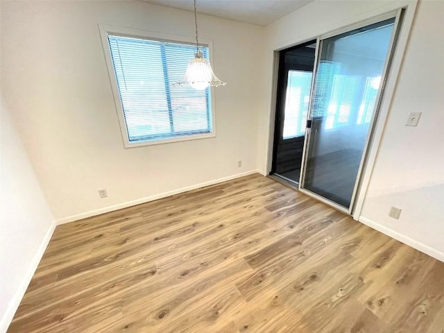 interior space with a healthy amount of sunlight, baseboards, a notable chandelier, and wood finished floors