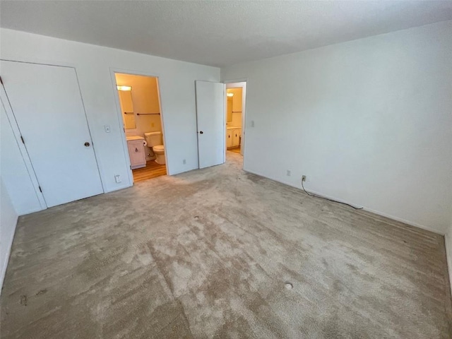 unfurnished bedroom with light carpet and ensuite bath