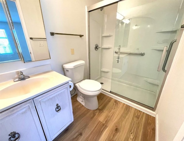 full bathroom featuring a stall shower, vanity, toilet, and wood finished floors