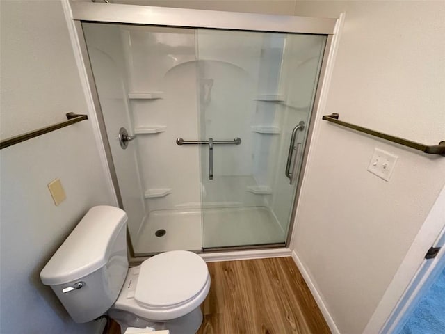full bathroom with toilet, baseboards, wood finished floors, and a stall shower