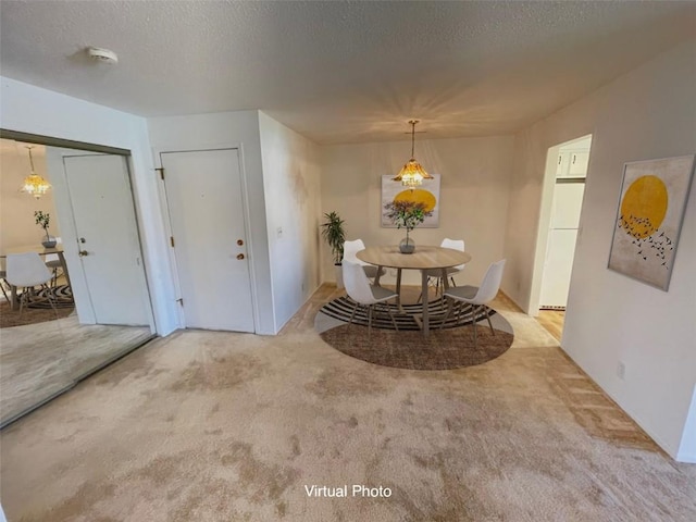 carpeted dining space featuring a textured ceiling