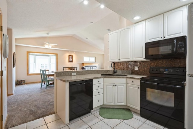 kitchen with a sink, a peninsula, white cabinetry, and black appliances