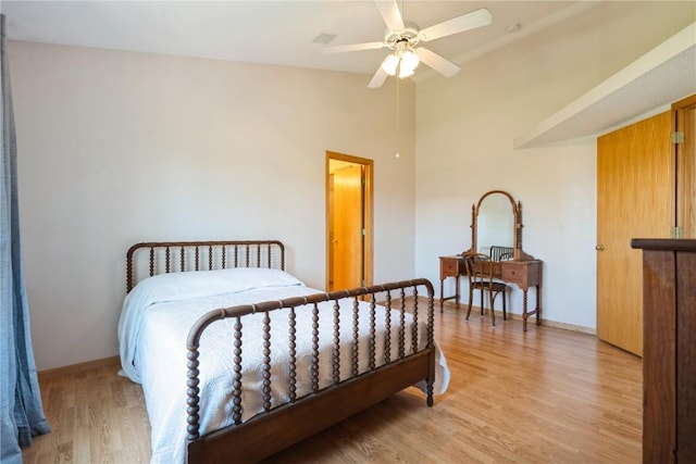 bedroom featuring lofted ceiling, baseboards, and light wood finished floors