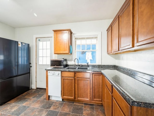 kitchen featuring freestanding refrigerator, a sink, dishwasher, stainless steel microwave, and healthy amount of natural light