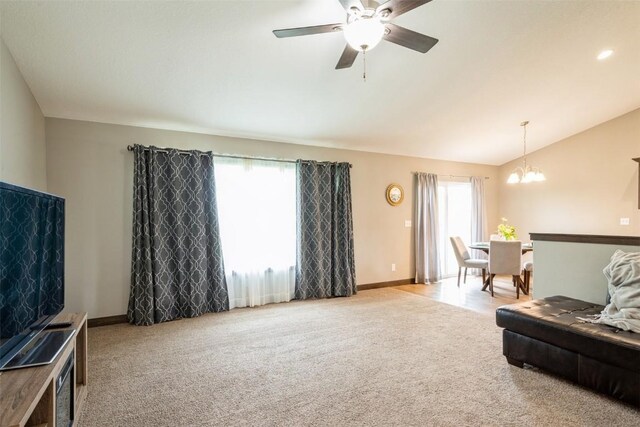 living area featuring carpet flooring, a chandelier, lofted ceiling, a ceiling fan, and baseboards