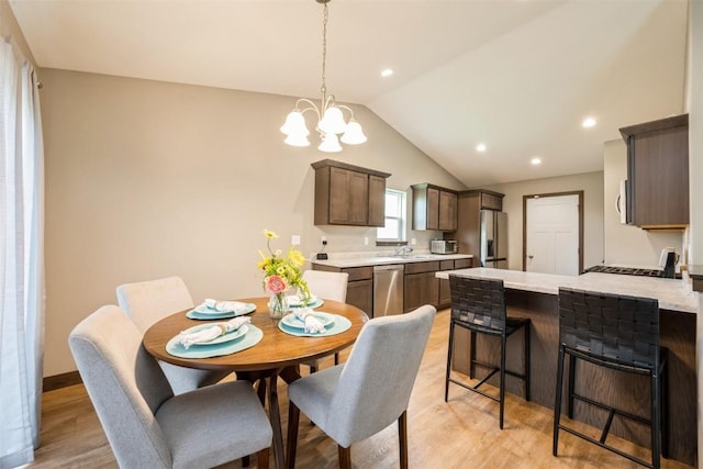 dining space featuring lofted ceiling, light wood finished floors, a chandelier, and recessed lighting