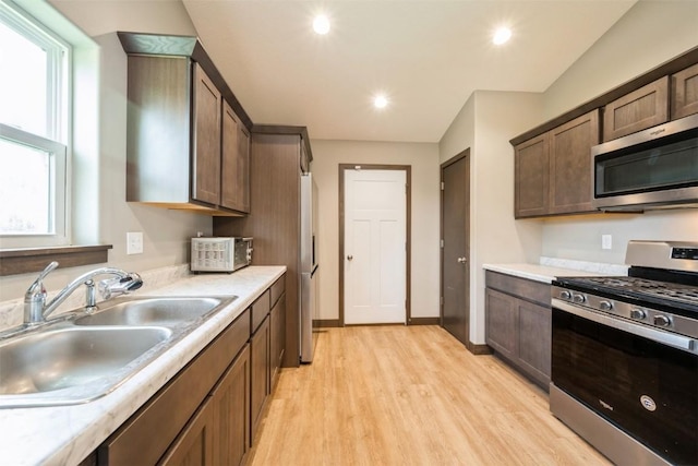 kitchen featuring appliances with stainless steel finishes, a sink, light wood-style flooring, light countertops, and recessed lighting