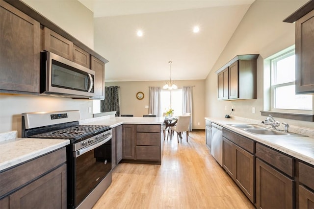 kitchen featuring stainless steel appliances, a sink, light wood finished floors, light countertops, and a chandelier