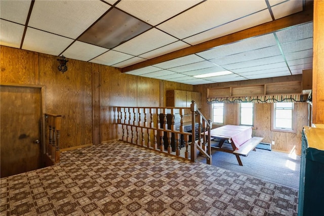 living area featuring wooden walls, a paneled ceiling, baseboards, and a baseboard radiator