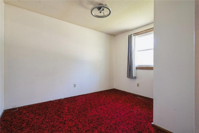 spare room featuring carpet floors and a textured ceiling