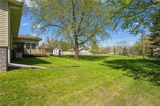 view of grassy yard featuring a shed, an outdoor structure, and a wooden deck
