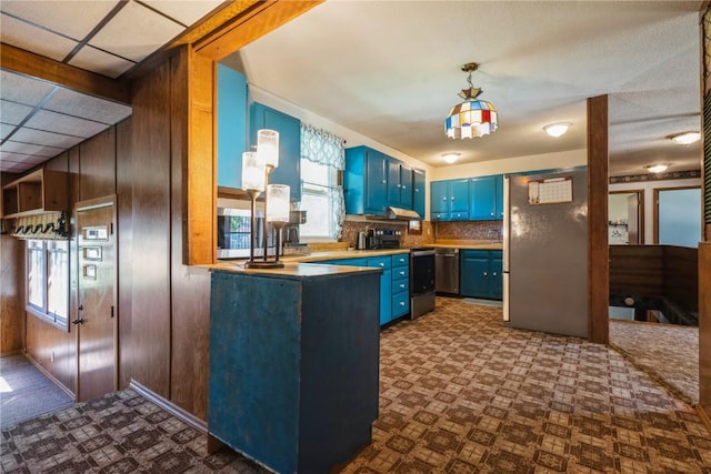 kitchen with blue cabinetry, stainless steel appliances, plenty of natural light, wooden walls, and a peninsula