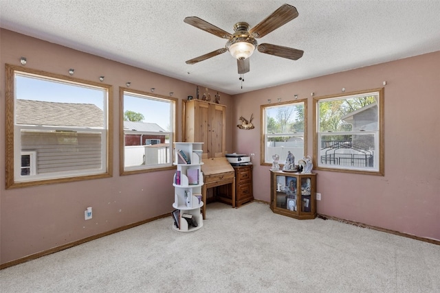 carpeted office space with ceiling fan, a textured ceiling, and baseboards