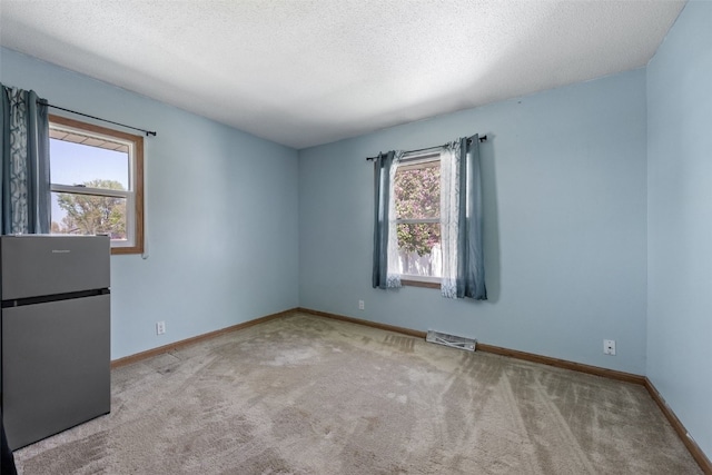 carpeted empty room featuring baseboards and a textured ceiling