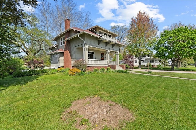 rear view of property featuring a porch, a chimney, and a lawn