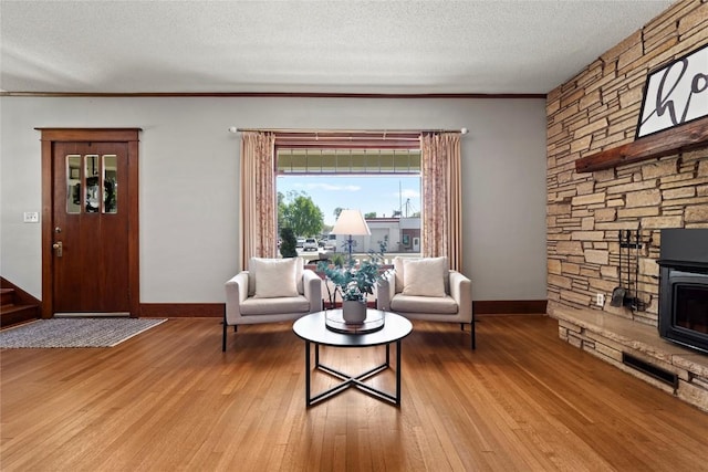 living area featuring wood finished floors, baseboards, a textured ceiling, and ornamental molding