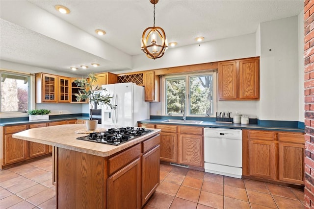 kitchen with white appliances, plenty of natural light, brown cabinets, a kitchen island, and a textured ceiling