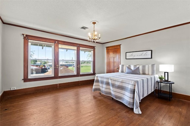 bedroom featuring a chandelier, wood finished floors, crown molding, baseboards, and a textured ceiling