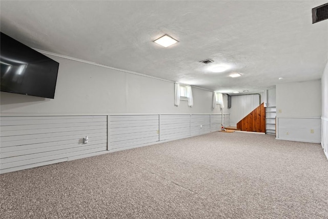 basement with carpet flooring, a textured ceiling, and wood walls