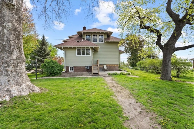 back of property with a lawn, a chimney, driveway, and roof with shingles