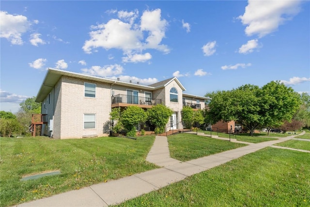 view of front of house featuring a front lawn, brick siding, and a balcony