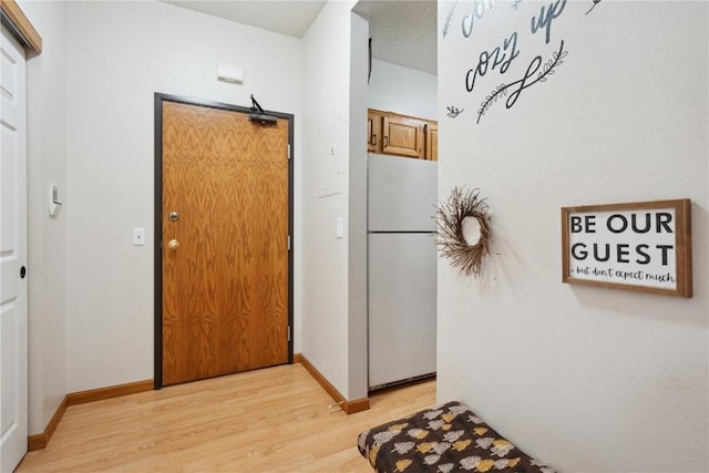 hallway featuring light wood-type flooring and baseboards
