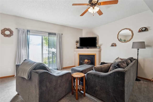 carpeted living room with ceiling fan, baseboards, a glass covered fireplace, and a textured ceiling