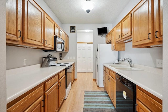 kitchen with white appliances, a sink, light wood-type flooring, light countertops, and a textured ceiling