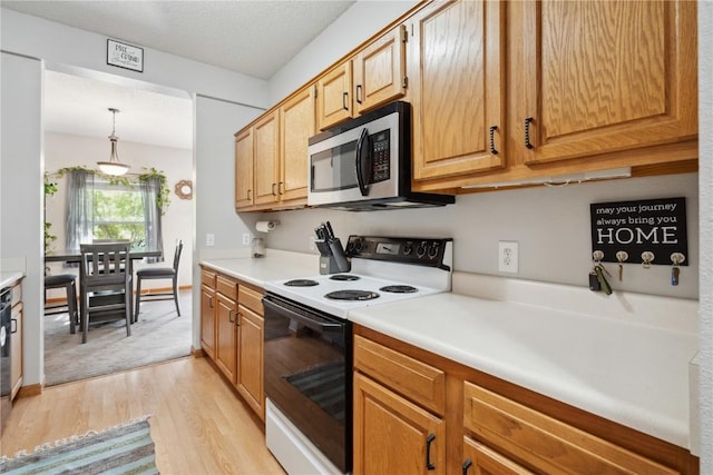 kitchen with range with electric stovetop, stainless steel microwave, light wood-style floors, and light countertops