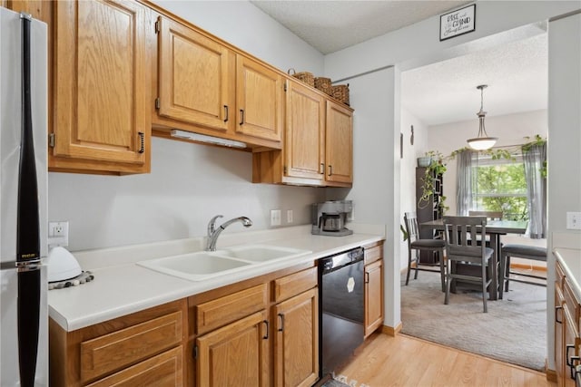 kitchen with dishwasher, a sink, freestanding refrigerator, light countertops, and pendant lighting