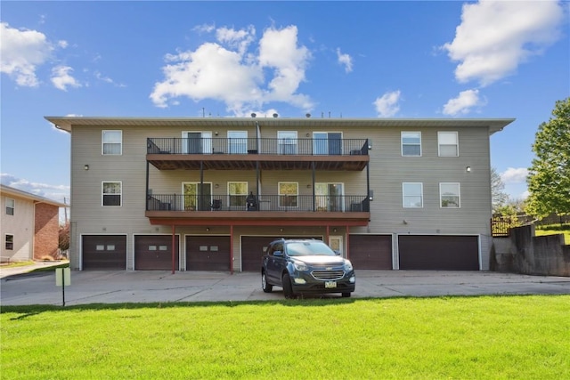 back of property with a balcony, a garage, and driveway