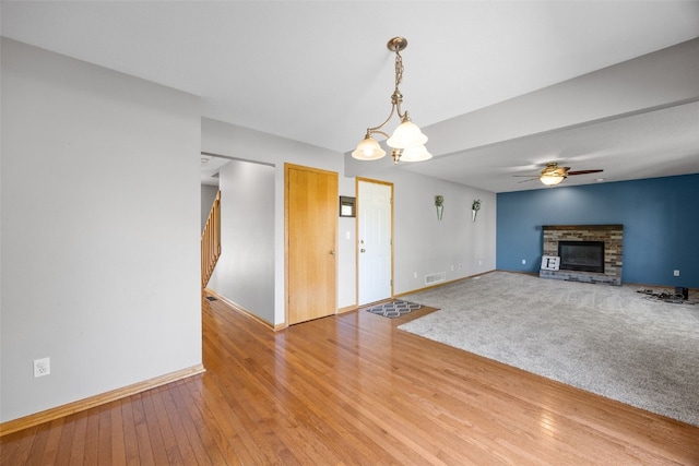 unfurnished living room with baseboards, a brick fireplace, light wood-style flooring, and ceiling fan