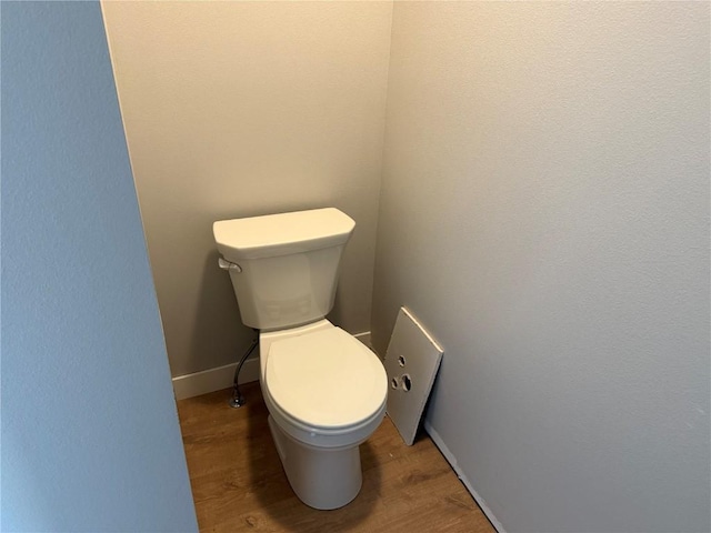 bathroom with wood finished floors, toilet, and baseboards