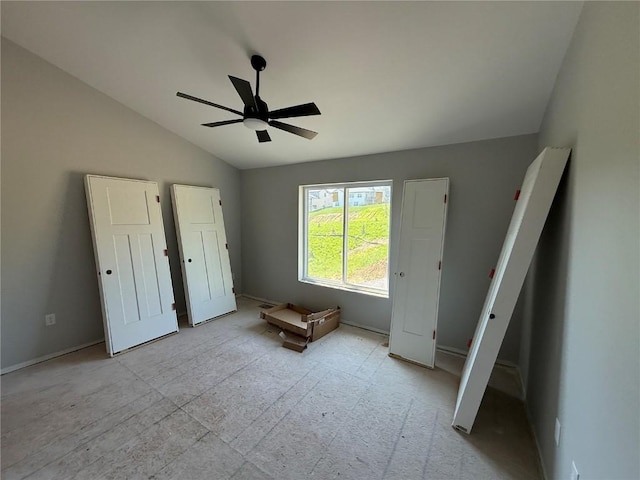 unfurnished bedroom featuring lofted ceiling, a ceiling fan, and baseboards