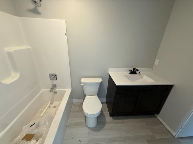 bathroom with toilet, baseboards, vanity, and shower / bath combination