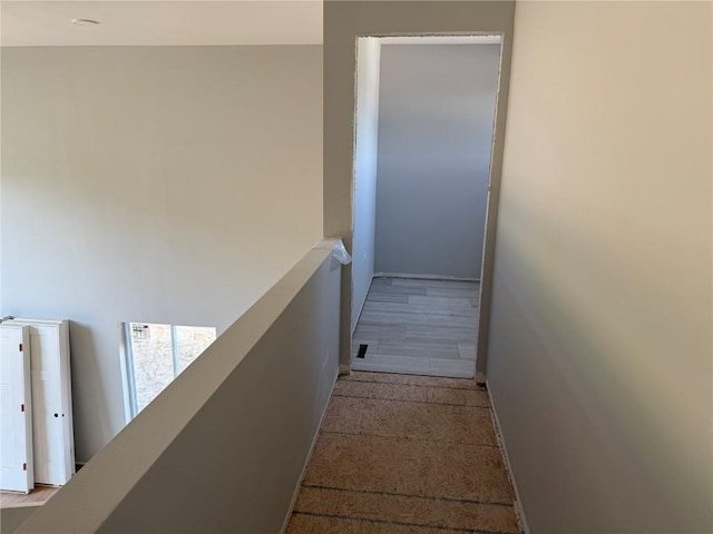 hall featuring baseboards and an upstairs landing