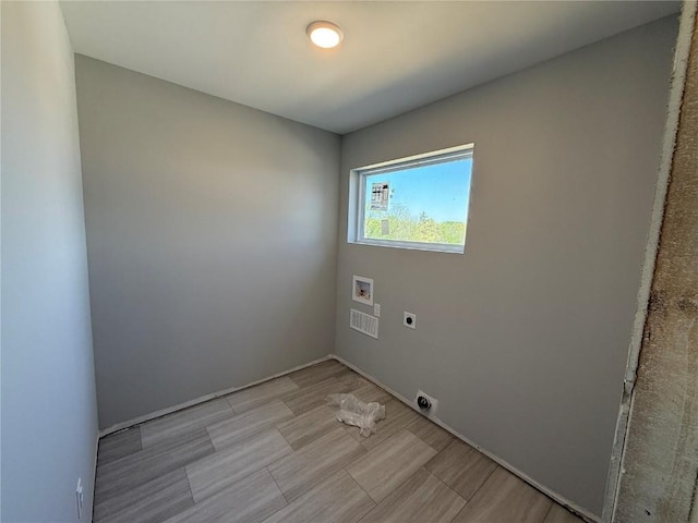 washroom with hookup for an electric dryer, washer hookup, light wood-style floors, and baseboards