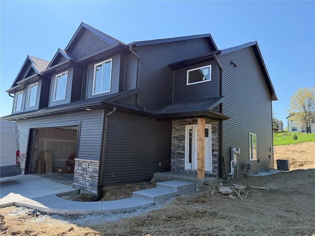 craftsman inspired home featuring stone siding, a garage, and central air condition unit