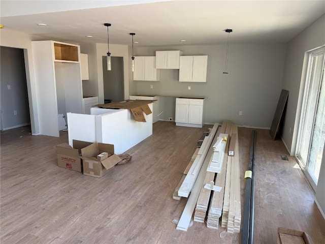kitchen featuring a kitchen island, wood finished floors, white cabinetry, recessed lighting, and decorative light fixtures