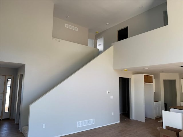 unfurnished living room featuring a towering ceiling, wood finished floors, and baseboards