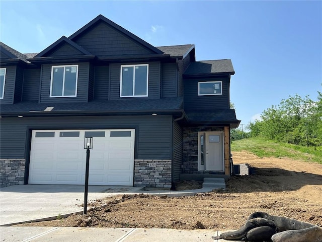 1301 Legend Dr, Tiffin, IA 52340 - craftsman-style home with stone siding, an attached garage, concrete driveway, and a shingled roof