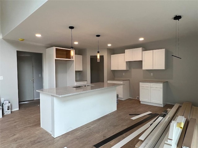 1301 Legend Dr, Tiffin, IA 52340 - kitchen featuring a kitchen island with sink, white cabinetry, wood finished floors, recessed lighting, and baseboards