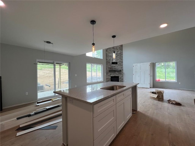 1301 Legend Dr, Tiffin, IA 52340 - kitchen featuring open floor plan, wood finished floors, a kitchen island with sink, a fireplace, and white cabinets